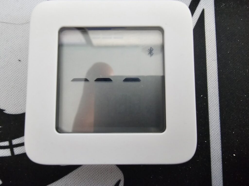 A photo of a thermometer with "---" on the screen and a Bluetooth icon lit up.